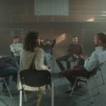 Grupo diverso participa de uma conversa de apoio em saúde mental dentro de um ginásio.