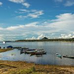 Barcos atracados em águas tranquilas de um rio, em uma paisagem amazônica.