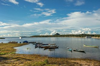 Barcos atracados em águas tranquilas de um rio, em uma paisagem amazônica.