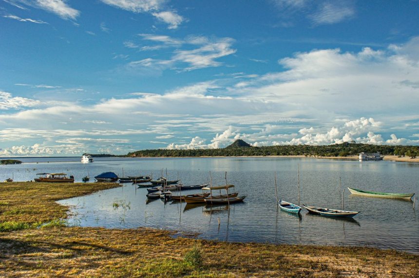 Barcos atracados em águas tranquilas de um rio, em uma paisagem amazônica.