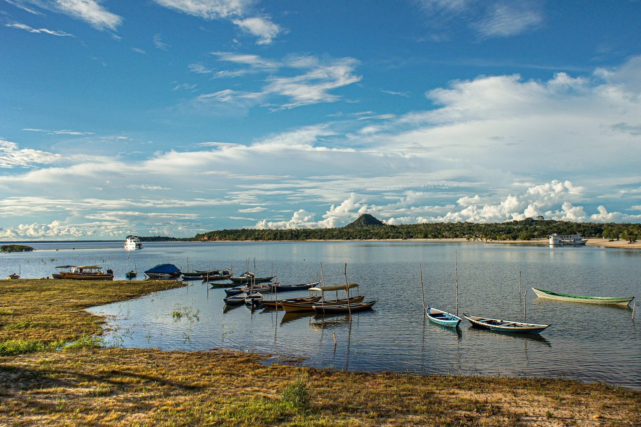 Barcos atracados em águas tranquilas de um rio, em uma paisagem amazônica.