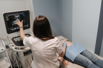 Profissional de saúde realiza exame de ultrassom em uma paciente em consultório médico.