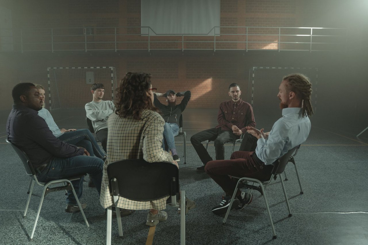 Grupo diverso participa de uma conversa de apoio em saúde mental dentro de um ginásio.
