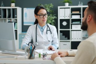 Médico conversa com uma paciente em uma clínica, discutindo opções de tratamento.